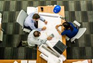 Photo of 3 people looking at some plans at a desk.