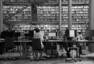 A black and white photo of people working at computers in a library.